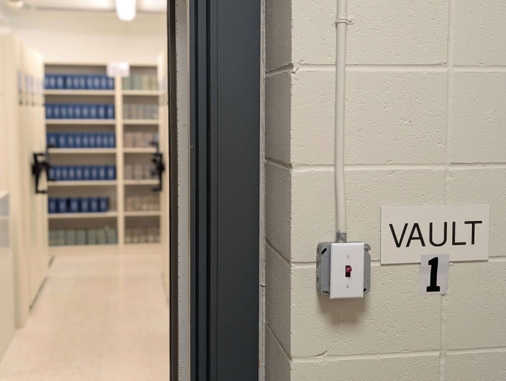 A doorway into a room full of books, labelled Vault 1.
