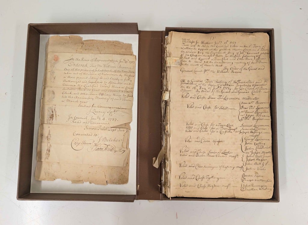 A brown box open to show loosely-bound pages of handwritten Waltham records.